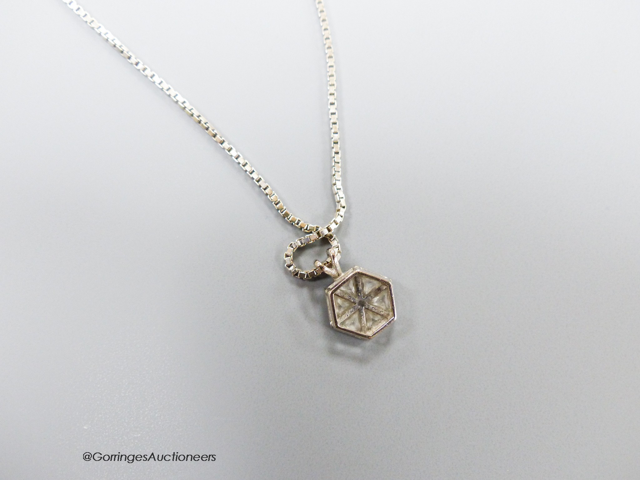 A white metal and six stone triangular diamond set hexagonal pendant, 9mm, pendant on an Italian 18ct white gold chain, 46cm, gross 6.4 grams.